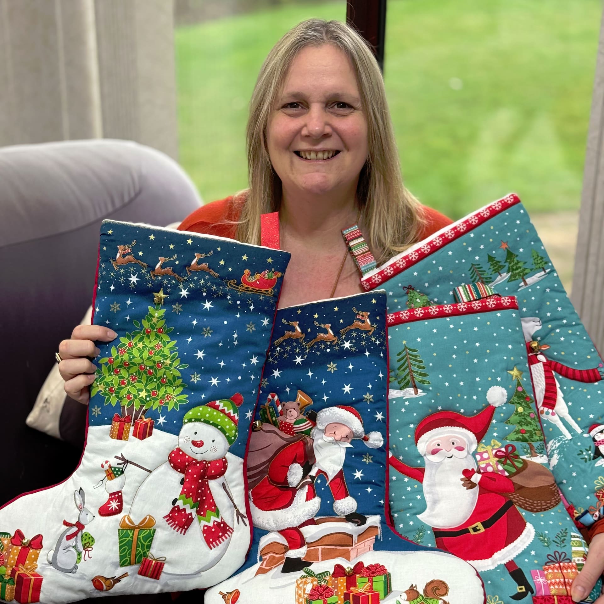 Angie Stewart, Owner, of Craft Making Ideas holding up 4 Makower Quilted Christmas Stockings