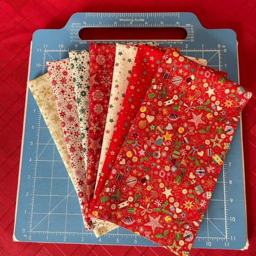 Makower Christmas 2025 seven piece fat quarter bundle folded with ruler for scale